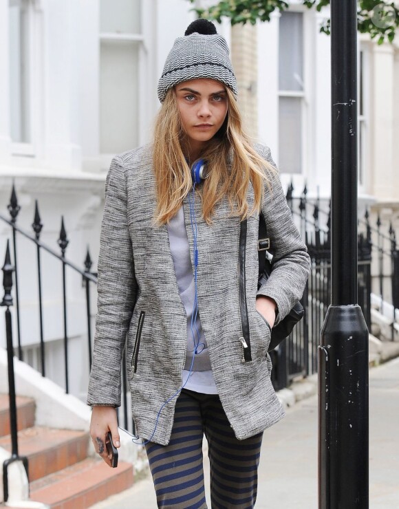 Cara Delevingne, bonnet et veste grise, se promène dans les rues de Londres. Le 12 juin 2013