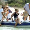 Kate Moss grimpe à bord d'un bateau gonflable avec Mario Testino et des membres de sa famille. Le 16 août 2013.