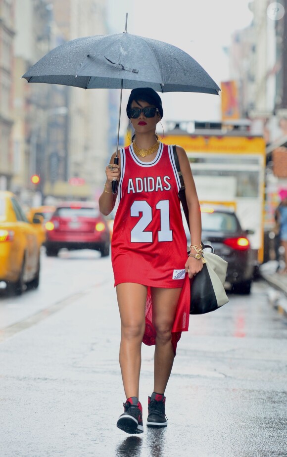 Rihanna, radieuse sous la pluie dans le quartier de SoHo à New York, porte des lunettes "Bowie" signées Le Specs, une robe adidas Originals by Jeremy Scott, un sac "Baylee" de Chloé et des baskets Air Jordan. Le 2 septembre 2013.