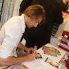 Camille Lacourt s'applique pour signer des autographes pour les 10 ans de la collection homme de chez Clarins, au Printemps Haussmann à Paris, le 19 septembre 2013