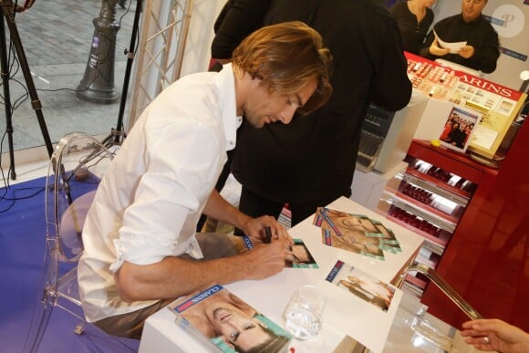 Camille Lacourt s'applique pour signer des autographes pour les 10 ans de la collection homme de chez Clarins, au Printemps Haussmann à Paris, le 19 septembre 2013
