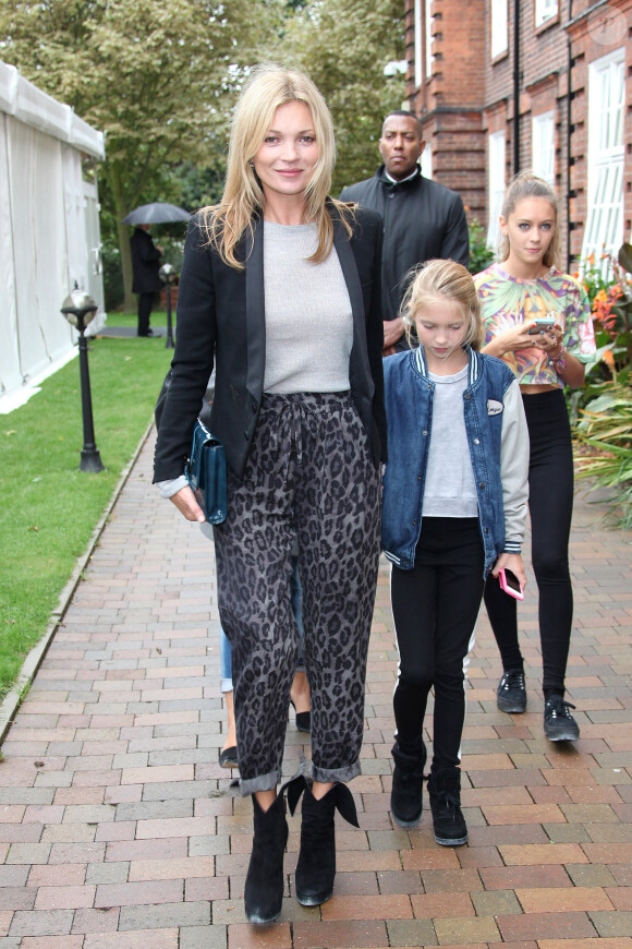 Kate Moss quitte le Topshop Show Space à Londres avec sa fille Lila Grace après le défilé Topshop Unique. Le top model de 39 ans porte un blazer noir, un sweater gris, un pantalon à imprimé léopard, une pochette Kate Moss for Longchamp et des bottines Azzedine Alaïa. Le 15 septembre 2013.