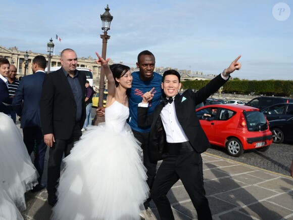 Usain Bolt prend la pose avec un couple de jeunes mariés sur la place de la Concorde à Paris, le 21 septembre 2013