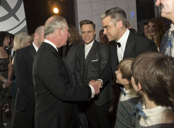 Le prince Charles saluant Robbie Williams sous le regard d'Olly Murs lors de la Royal Variety Performance du 25 novembre 2013 au Palladium, à Londres.