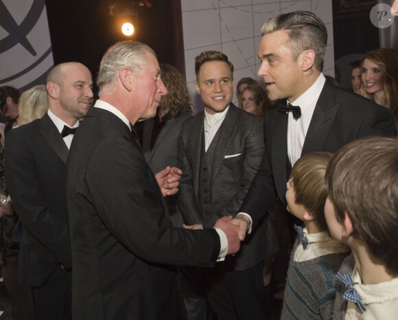 Le prince Charles saluant Robbie Williams sous le regard d'Olly Murs lors de la Royal Variety Performance du 25 novembre 2013 au Palladium, à Londres.