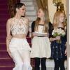 Jessie J se met à hauteur de la jeune Arabella Mansfield, chargée de remettre les programmes au prince Charles et à la duchesse Camilla, au moment de leur arrivée à la Royal Variety Performance du 25 novembre 2013 au Palladium, à Londres.