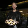Calvin Harris, de bonne humeur, propose des cupcakes aux photographes postés devant chez lui au soir de l'anniversaire de sa petite amie, la chanteuse Rita Ora. Londres, le 26 novembre 2013.