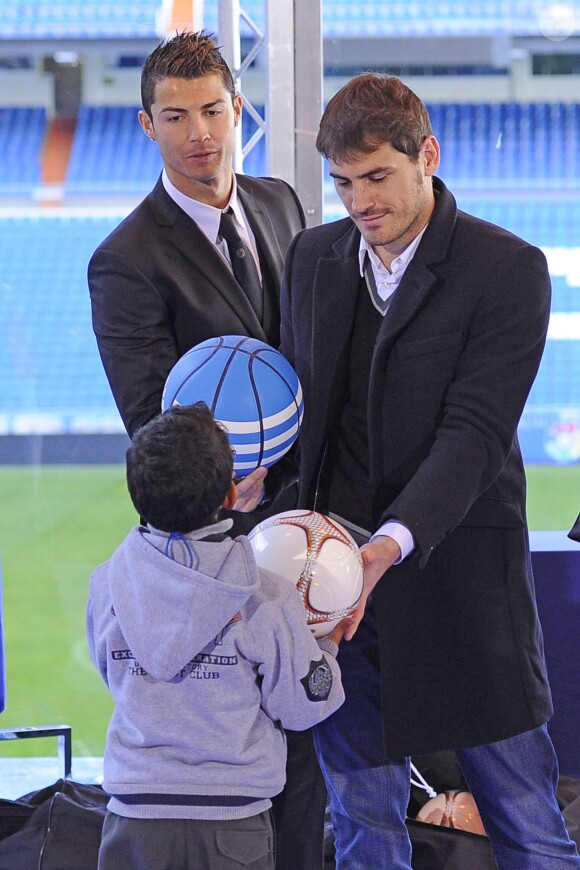 Cristiano Ronaldo et Iker Casillas tentent de soudoyer un enfant à coup de ballons lors du lancement de la campagne "A Noël aucun enfant sans cadeau" de la fondation de l'équipe du Real Madrid au stade Santiago Bernabeu de Madrid, le 16 décembre 2013