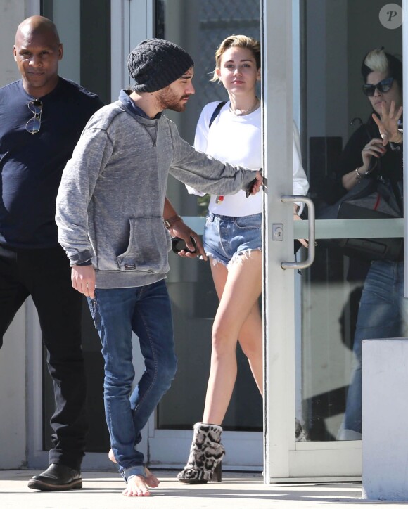 Miley Cyrus et son entourage arrivent à l'aéroport de Miami, le 18 décembre 2013.