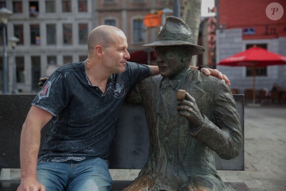 Exclusif - Pierre Simenon (Fils cadet de Georges Simenon et frère de Marc Simenon, le mari de Mylène Demongeot, et auteur du livre "Au nom du sang versé") pose avec la statue de Georges Simenon sur un banc dans les rues de Liège, le 27 avril 2014.