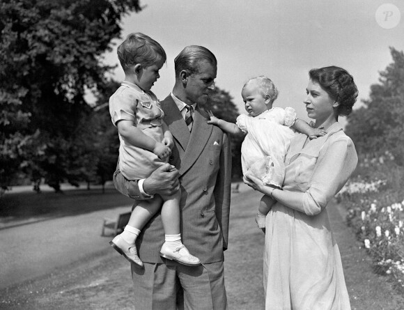 La princesse Anne enfant dans les bras de la reine Elizabeth II en août 1951 à Clarence House. Le prince Philip tient lui le prince Charles.