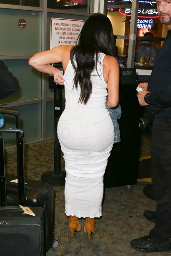 Kim Kardashian, parfaitement moulée dans une robe blanche Faith Connexion et chaussée de sandales Hermès à l'aéroport de Burbank. Le 13 mai 2015.