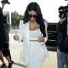 Kim Kardashian à l'aéroport de Los Angeles, porte des lunettes Saint Laurent, un blazer blanc, un top et une jupe Wolford, et des sandales beiges. Le 9 mai 2015.