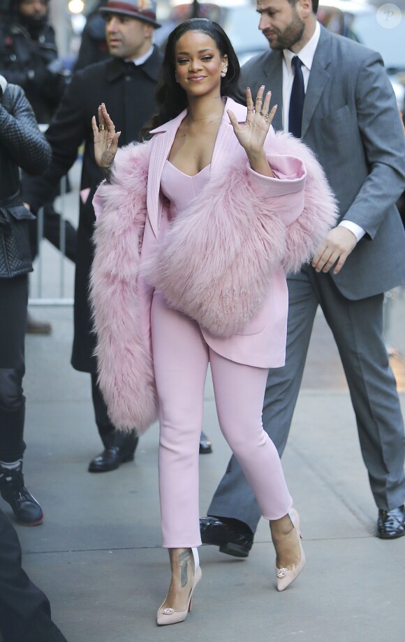 Rihanna arrive sur le plateau de l'émission "Good Morning America" à New York, tout de rose vêtue avec un manteau, une combinaison bustier et une écharpe en fourrure Pascal Millet (collection automne-hiver 2015-2016) et de souliers Christian Louboutin. Le 13 mars 2015.