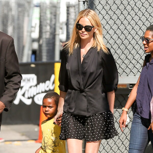 Charlize Theron arrive sur le plateau de l'émission "Jimmy Kimmel Live!" avec son fils Jackson à Hollywood, habillée d'une veste kimono noire, d'une jupe à poids et de baskets Isabel Marant Étoile (modèle Bart). Le 20 juillet 2015.