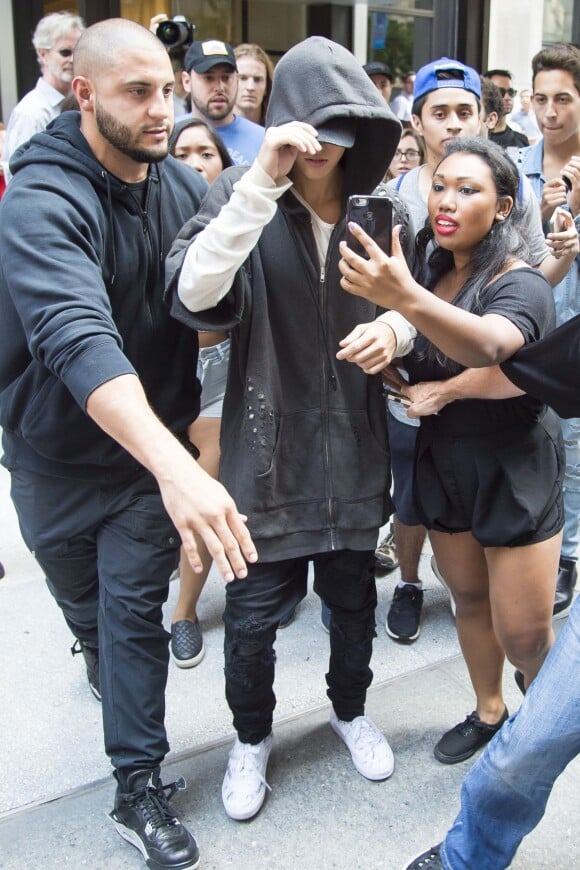Justin Bieber, assailli par ses fans, se promène avec ses gardes du corps dans les rues de Manhattan à New York. Le 24 août 2015