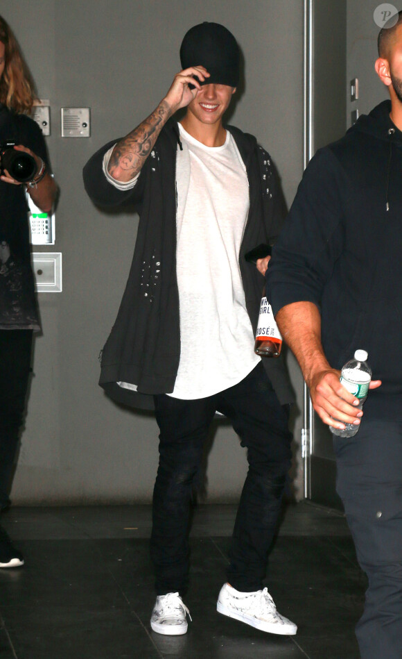 Justin Bieber, porte une bouteille de vin à la main, à la sortie d'un immeuble à New York, le 24 aout 2015