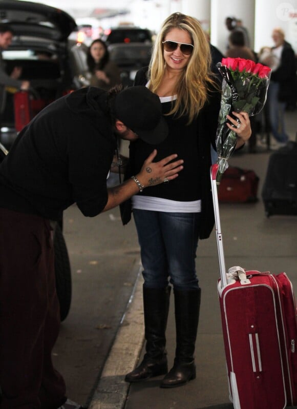 Tiffany Thornton enceinte arrive à l'aéroport de Los Angeles, son mari Chris Carney venu la chercher lui embrasse le ventre, le 24 mars 2012