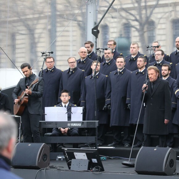 Johnny Hallyday, accompagné par Yodelice et Yarol Poupaud, chante "Un dimanche de janvier" en hommage aux victimes des attentats de janvier et novembre. Place de la République à Paris, le 10 janvier 2016.