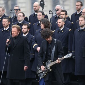 Johnny Hallyday, accompagné par Yodelice et Yarol Poupaud, chante "Un dimanche de janvier" en hommage aux victimes des attentats de janvier et novembre. Place de la République à Paris, le 10 janvier 2016.