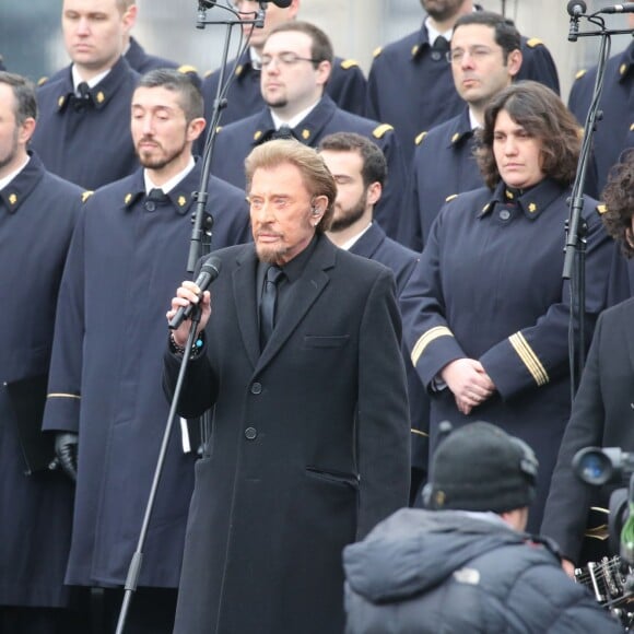 Johnny Hallyday, accompagné par Yodelice et Yarol Poupaud, chante "Un dimanche de janvier" en hommage aux victimes des attentats de janvier et novembre. Place de la République à Paris, le 10 janvier 2016.