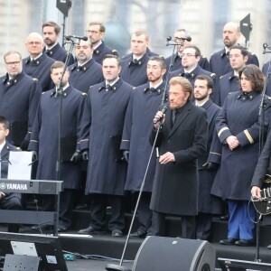 Johnny Hallyday, accompagné par Yodelice et Yarol Poupaud, chante "Un dimanche de janvier" en hommage aux victimes des attentats de janvier et novembre. Place de la République à Paris, le 10 janvier 2016.