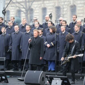 Johnny Hallyday, accompagné par Yodelice et Yarol Poupaud, chante "Un dimanche de janvier" en hommage aux victimes des attentats de janvier et novembre. Place de la République à Paris, le 10 janvier 2016.