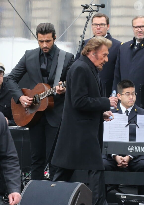 Johnny Hallyday, accompagné par Yodelice et Yarol Poupaud, chante "Un dimanche de janvier" en hommage aux victimes des attentats de janvier et novembre. Place de la République à Paris, le 10 janvier 2016.