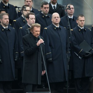 Johnny Hallyday, accompagné par Yodelice et Yarol Poupaud, chante "Un dimanche de janvier" en hommage aux victimes des attentats de janvier et novembre. Place de la République à Paris, le 10 janvier 2016.