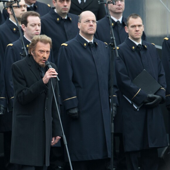 Johnny Hallyday, accompagné par Yodelice et Yarol Poupaud, chante "Un dimanche de janvier" en hommage aux victimes des attentats de janvier et novembre. Place de la République à Paris, le 10 janvier 2016.