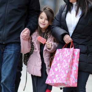 Suri Cruise, souriante, deguste un esquimau alors qu'elle se promene avec sa nounou et son garde du corps a New York, le 11 decembre 2013.