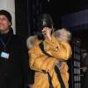 Rihanna quitte le Tramp à Londres, habillée d'un duffle-coat jaune Burberry et d'une robe en soie Rosetta Getty. Une casquette à l'effigie de la boîte de nuit londonienne Tramp et des lunettes de soleil Adam Selman x Le Specs accessoirisent sa tenue. Le 24 février 2016.
