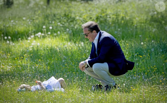 La princesse Leonore de Suède fait une pause allongée dans l'herbe sous le regard amusé et attendri de son père Christopher O'Neill lors de sa première visite dans le Gotland, dont elle détient le titre de duchesse, à Visby le 3 juin 2016.