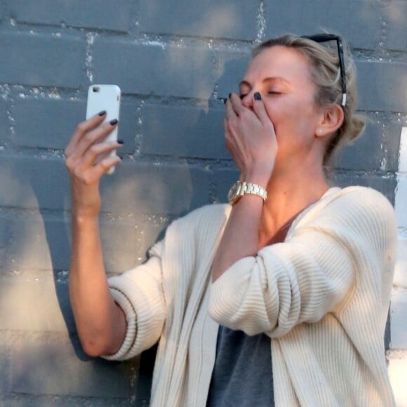 Exclusif - Charlize Theron s'échappe dans la rue quelques instants pour discuter et plaisanter en FaceTime avec un mystérieux inconnu à Hollywood. Elle s'amuse à faire un doigt d'honneur et envoi un baiser à son interlocuteur avant de raccrocher. Le 5 juillet 2016