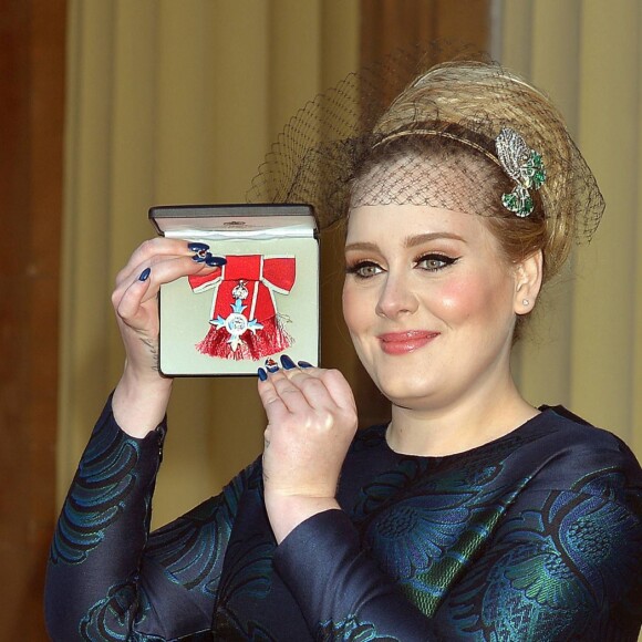 La chanteuse Adele (Adele Adkins) pose avec sa medaille (MBE), apres avoir ete decoree par le prince Charles, prince de Galles pour ses talents musicaux lors d'une ceremonie au palais de Buckingham a Londres, le 19 decembre 19, 2013.19/12/2013 - Londres