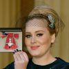 La chanteuse Adele (Adele Adkins) pose avec sa medaille (MBE), apres avoir ete decoree par le prince Charles, prince de Galles pour ses talents musicaux lors d'une ceremonie au palais de Buckingham a Londres, le 19 decembre 19, 2013.