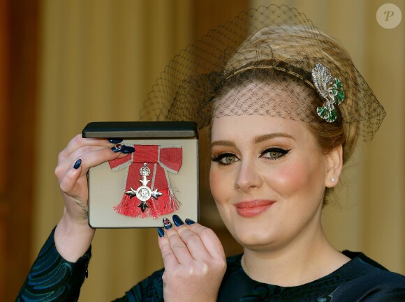 La chanteuse Adele (Adele Adkins) pose avec sa medaille (MBE), apres avoir ete decoree par le prince Charles, prince de Galles pour ses talents musicaux lors d'une ceremonie au palais de Buckingham a Londres, le 19 decembre 19, 2013.