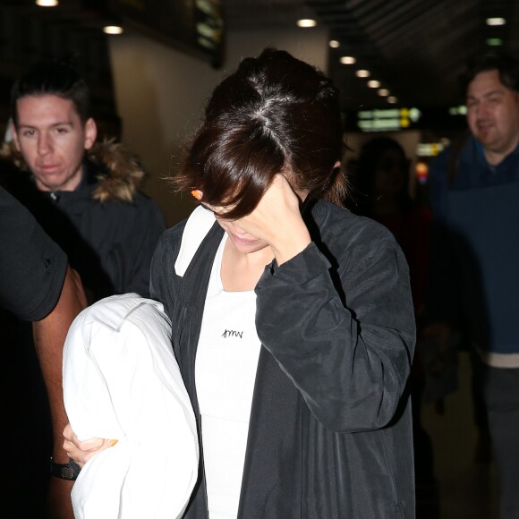 Selena Gomez se cache des photographes à son arrivée à l'aéroport de Melbourne. Australie, le 5 août 2016