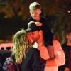 Exclusif - Hilary Duff embrasse son compagnon Jason Walsh (qui porte son fils Luca sur ses épaules!) à la sortie d'un marché à Los Angeles, le 31 octobre 2016.