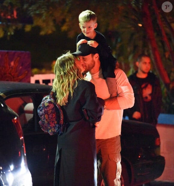 Exclusif - Hilary Duff embrasse son compagnon Jason Walsh (qui porte son fils Luca sur ses épaules!) à la sortie d'un marché à Los Angeles, le 31 octobre 2016.
