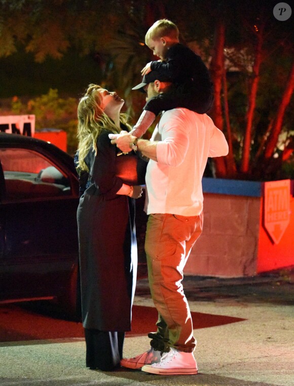Exclusif - Hilary Duff embrasse son compagnon Jason Walsh (qui porte son fils Luca sur ses épaules!) à la sortie d'un marché à Los Angeles, le 31 octobre 2016.