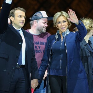 Morgan Simon (l'homme à la casquette), Emmanuel Macron, élu président de la république, et sa femme Brigitte Macron (Trogneux), saluent les militants devant la pyramide au musée du Louvre à Paris, après sa victoire lors du deuxième tour de l'élection présidentielle. Le 7 mai 2017.