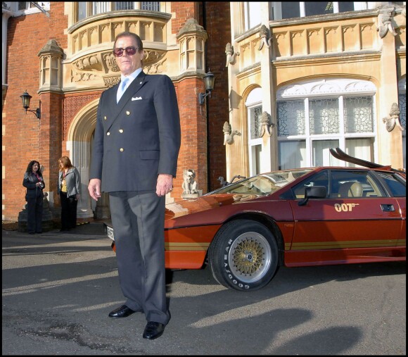Roger Moore posant avec les voitures originales de James Bond en 2008 à Londres