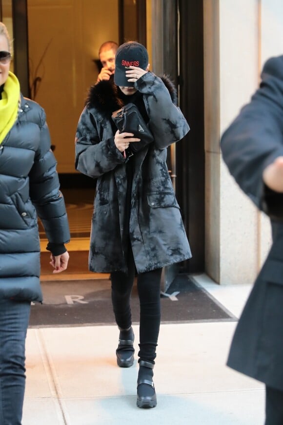 Bella Hadid quitte son appartement à New York, habillée d'une parka Yves Salomon for Opening Ceremony et chaussée de baskets iRi. Une casquette Balenciaga et une banade en nylon Prada accessoirisent sa tenue. Le 2 février 2018.