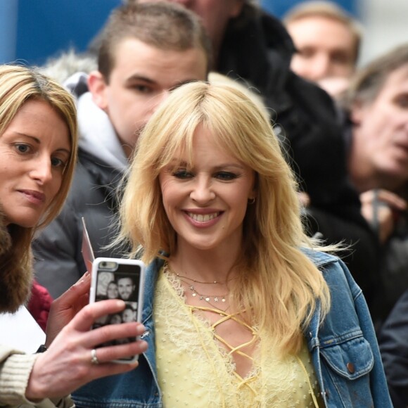Kylie Minogue, en robe jaune et veste en jean, à la sortie de Quay House à Salford, près de Manchester. Le 23 mars 2018.