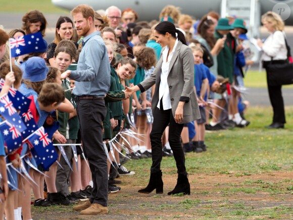 Le prince Harry, duc de Sussex et sa femme Meghan Markle, duchesse de Sussex (enceinte) sont accueillis par des élèves australiens à leur arrivée à Dubbo en Australie dans le cadre de leur première tournée officielle, le 17 octobre 2018.