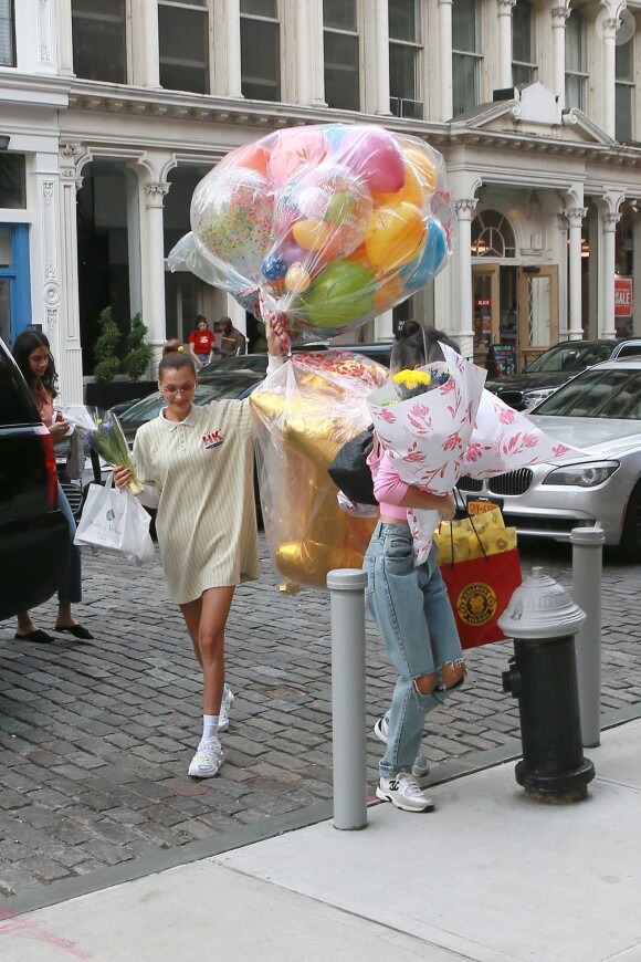 Bella Hadid arrive les bras chargés de ballons et fleurs au domicile de sa soeur Gigi Hadid pour son anniversaire à New York, le 23 avril 2019.