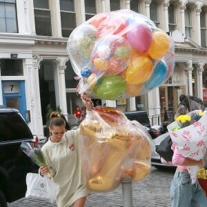 Bella Hadid arrive les bras chargés de ballons et fleurs au domicile de sa soeur Gigi Hadid pour son anniversaire à New York, le 23 avril 2019.