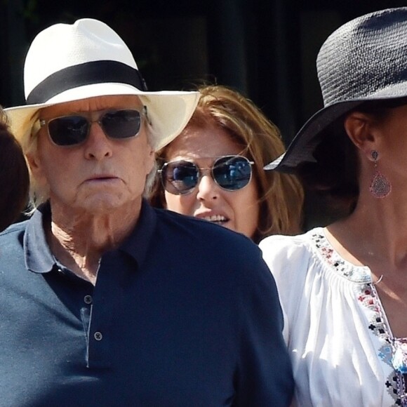 Michael Douglas et sa femme Catherine Zeta-Jones - L'acteur hollywoodien M.Douglas et sa femme C.Zeta-Jones sont en vacances à Portofino, en Italie. Le couple se promène en ville, main dans la main, Catherine est très élégante dans sa robe blanche avec son chapeau, tandis que Michael, âgé de 74 ans, porte une tenue plus décontractée avec son polo bleu et son short rose. Michael fait profiter de la vue à son interlocuteur lors d'un appel en face time alors qu'il revenait à son yacht. Portofino, le 31 juillet 2019.
