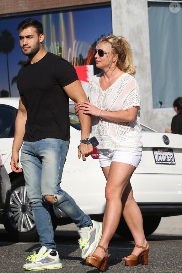 Exclusif - Britney Spears et son compagnon Sam Asghari sont allés déjeuner dans le restaurant 'Le Pain Quotidien' à Beverly Hills. Britney porte une blouse blanche transparente qui laisse entrevoir ses tétons. Le couple semble très amoureux, ils se tiennent la main alors qu'ils traversent la rue, le 12 juillet 2019.